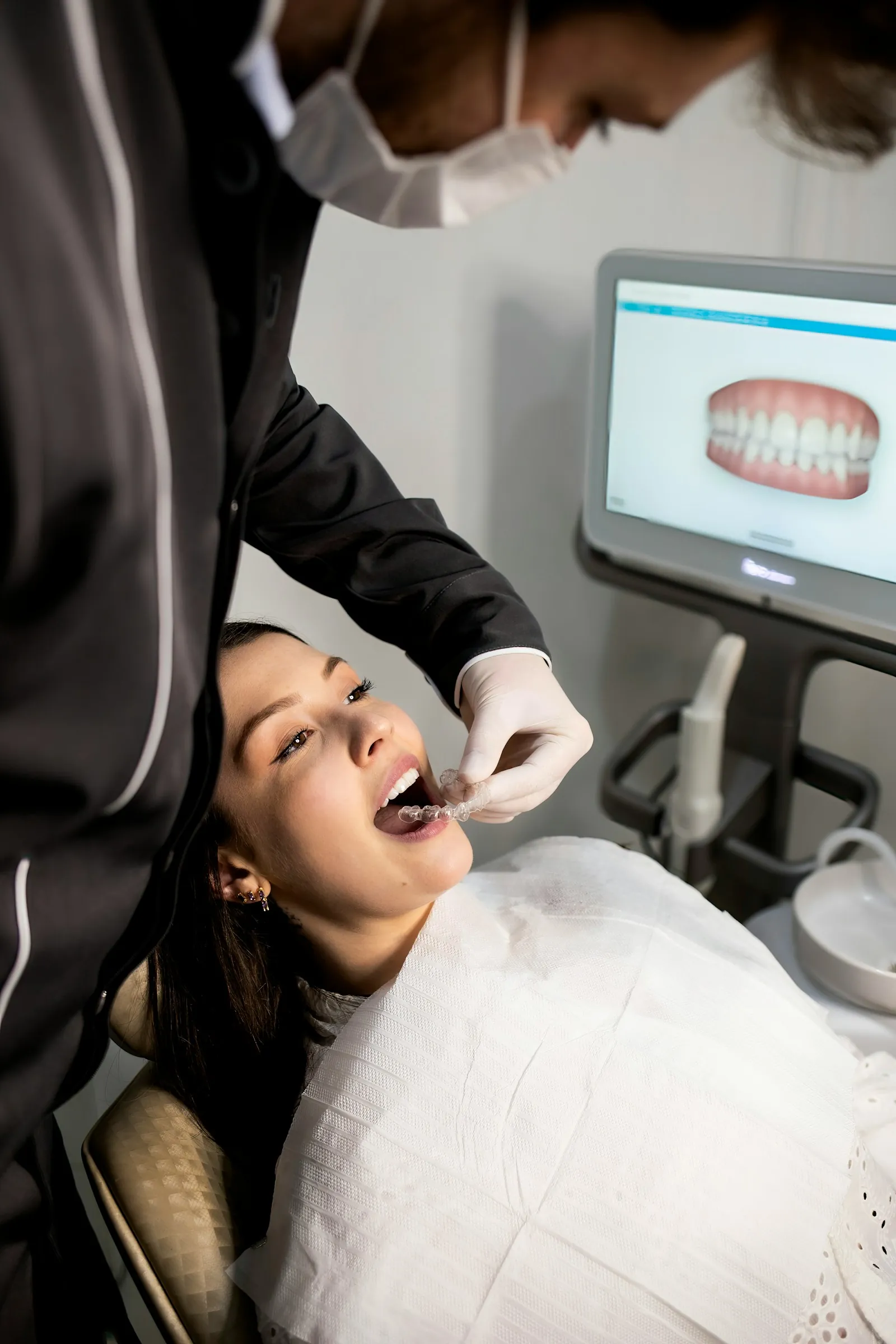 Profissional de odontologia em atendimento, com o escaneamento da arcada na tela ao fundo